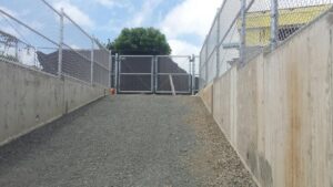 A chain-link fence and gate installed at the bottom of a sloped concrete path by David's Fencing Inc. in Waipahu, HI.