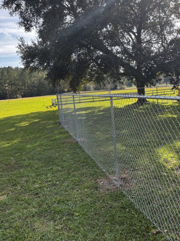A newly installed chain-link fence running along a property line by Dallas' Custom Carpentry in Alexandria, LA.