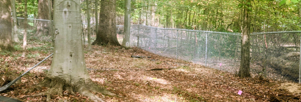 A durable chain-link fence installed in a wooded residential area by B&L Fence Co in Youngstown, OH.