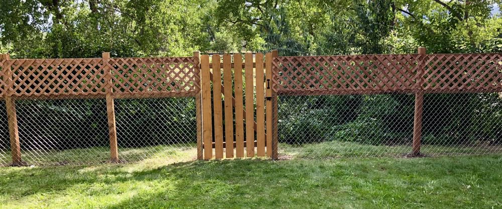 A chain link fence with a decorative lattice top and a wooden gate installed by 2 Guys & A Girl Lawn Care in Thornton, CO.