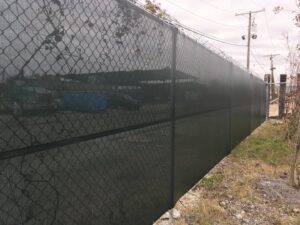 A chain-link fence with a privacy screen and barbed wire installed by Amko Fence Co. in Kenner, LA.
