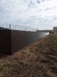 A chain link fence with razor wire securing an agricultural area by Angel Fencing Inc. in Fresno, CA