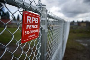 A chain-link fence with an RPB Fence business sign attached, showcasing their work in Salem, OR
