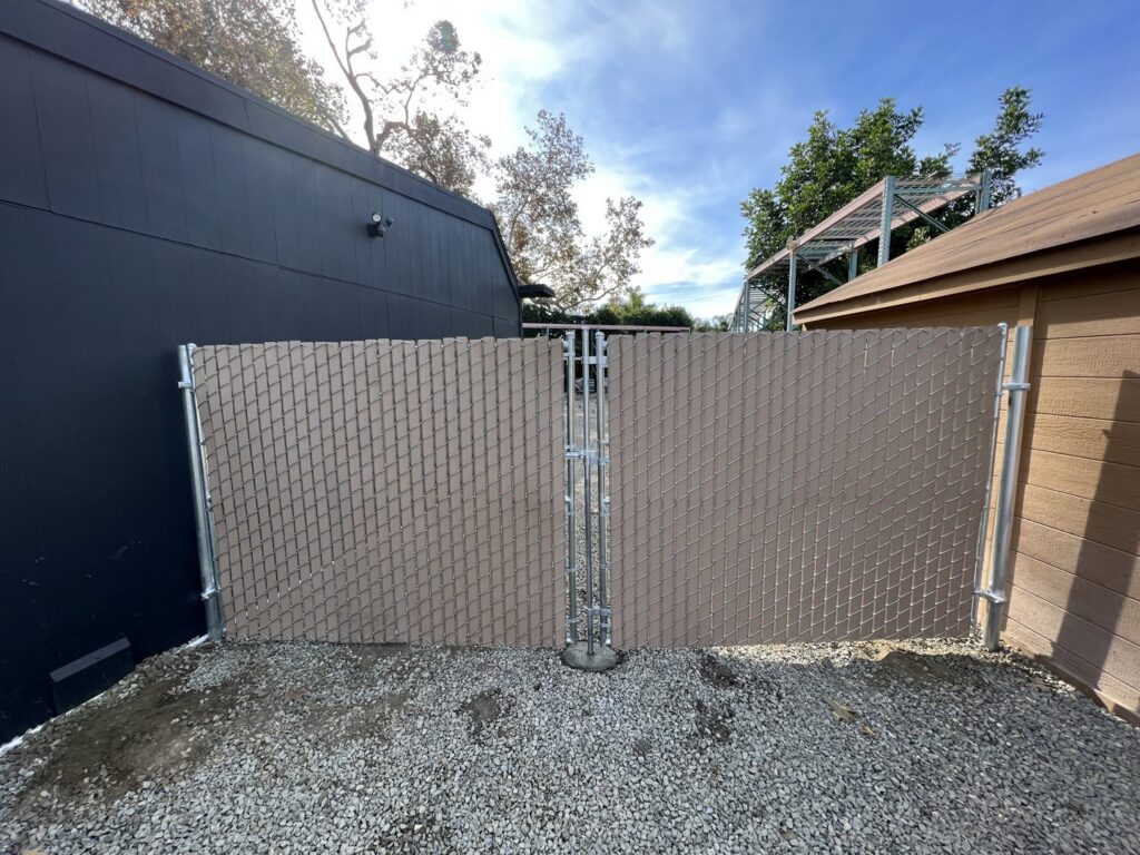 A chain link fence with privacy slats and an integrated gate installed by No Limit Fence Company in Huntington Beach, CA.