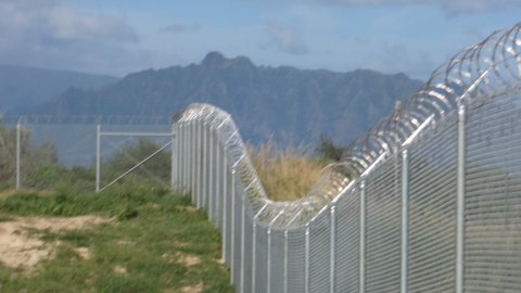 A long chain-link fence with razor wire on top, installed by David's Fencing Inc. in Waipahu, HI.