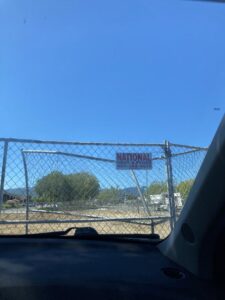 A chain-link fence with a "Rent-A-Fence" sign viewed from inside a car, provided by National Construction Rentals in Las Vegas, NV.