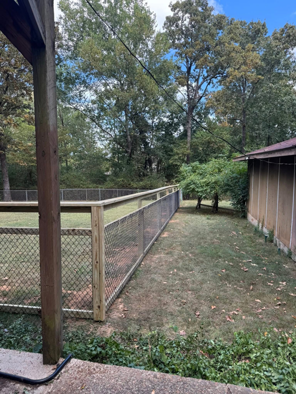 Chain-link fence with a wooden top rail and posts, likely for an animal enclosure, installed by Faithful Fencing LLC in Batesville, AR.