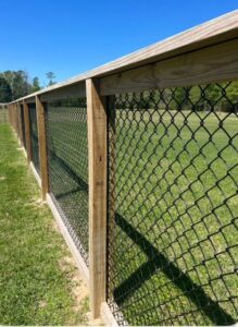 A chain-link fence with sturdy wooden posts and a top rail, installed by JBunlimitedfencingllc in Savannah, GA.