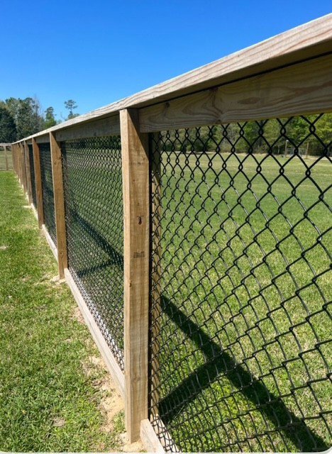 A chain-link fence with sturdy wooden posts and a top rail, installed by JBunlimitedfencingllc in Savannah, GA.