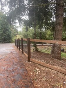 A chain link fence with sturdy wooden posts and a wooden top rail, installed by PNW FENCE in Lewiston, ID.