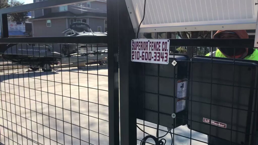 A chain link gate with a solar-powered opener and business signage by Superior Fence Co. of San Antonio, TX.