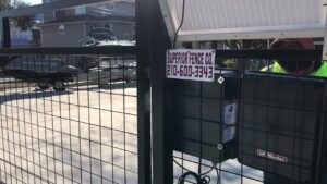 A chain link gate with a solar-powered opener and business signage by Superior Fence Co. of San Antonio, TX.