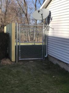 A chain link gate installed next to a house, connecting to a wood fence by Budget Fence of Ohio in Cleveland, OH.