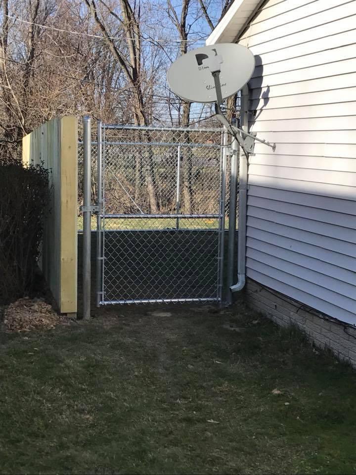 A chain link gate installed next to a house, connecting to a wood fence by Budget Fence of Ohio in Cleveland, OH.