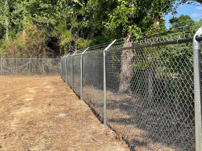 A robust chain link security fence with barbed wire installed by First Class Fence and Landscape LLC in Birmingham, AL.