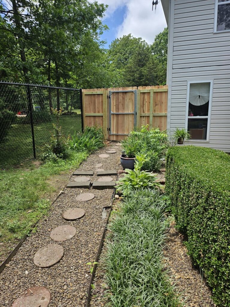 A backyard featuring a combination of black chain-link and wooden privacy fence with a gate, installed by Superior Fence & Rail of Arkansas in Springdale, AR.
