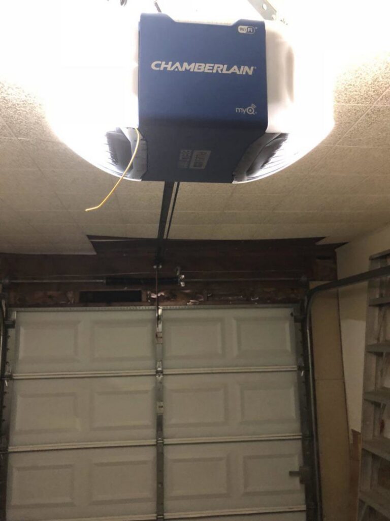 A newly installed Chamberlain garage door opener above a white sectional door by OklaHome Overhead Doors in Tulsa, OK