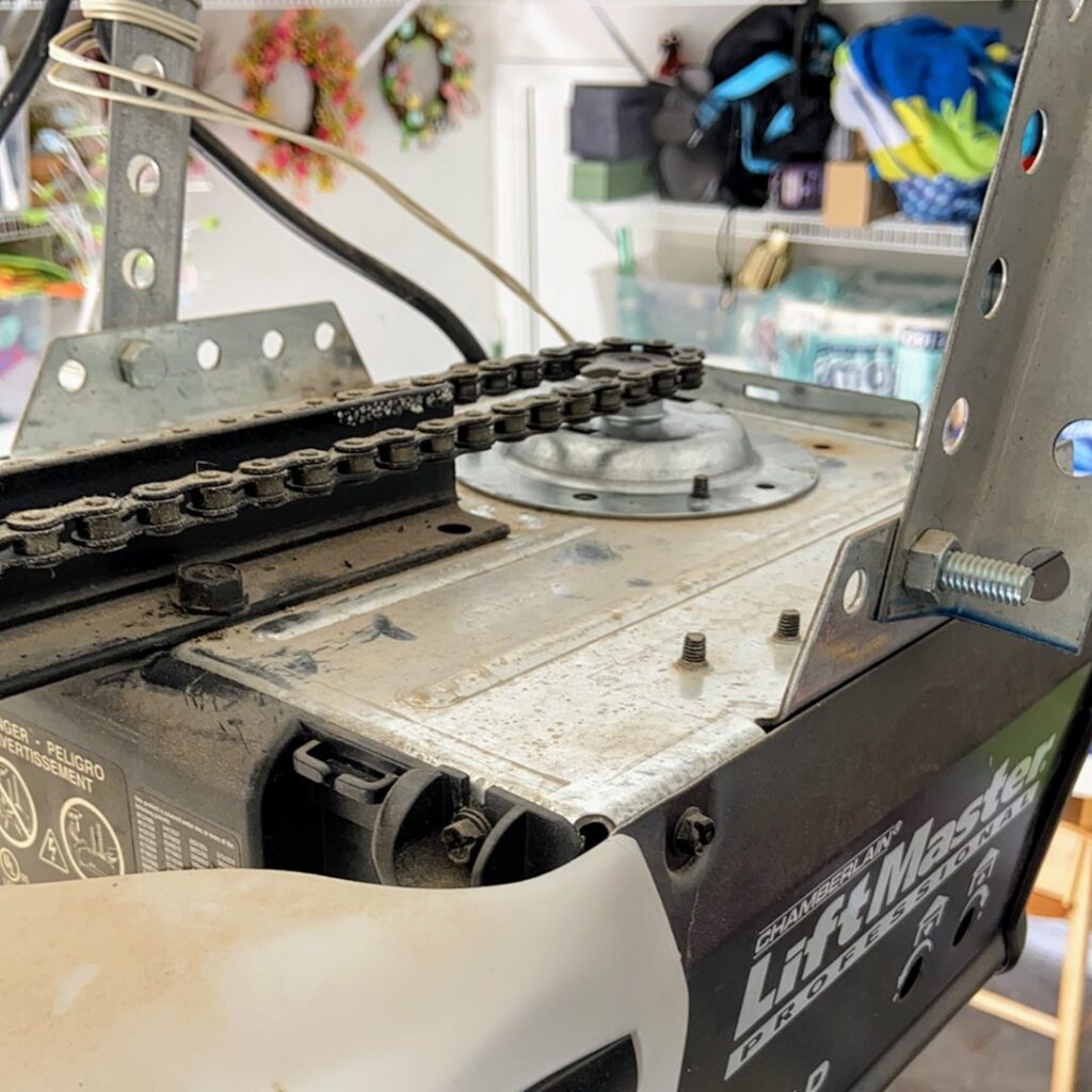 A close-up of a Chamberlain LiftMaster garage door opener motor and chain drive system by MGG Garage Door Service in San Tan Valley, AZ