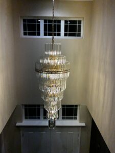 A large, multi-tiered chandelier installed in a tall entryway by Watts Up Electric in Crystal Lake, IL.