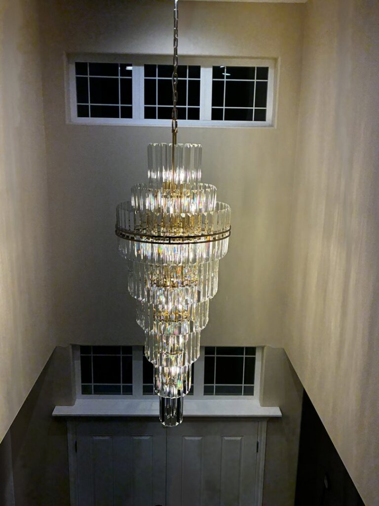 A large, multi-tiered chandelier installed in a tall entryway by Watts Up Electric in Crystal Lake, IL.