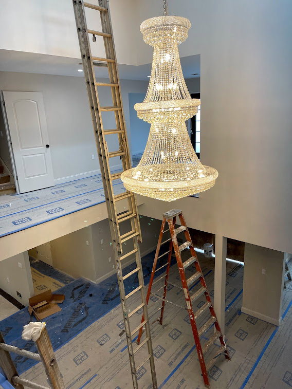 Installation of a large chandelier in a high-ceiling room, requiring specialized electrical work by D&M Master Electric LLC in Newark, NJ.