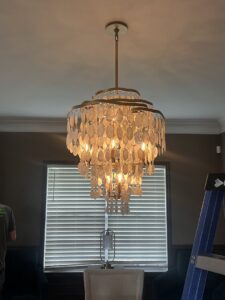 A large decorative chandelier being installed in a home by Shocking Solutions in Knoxville, TN.
