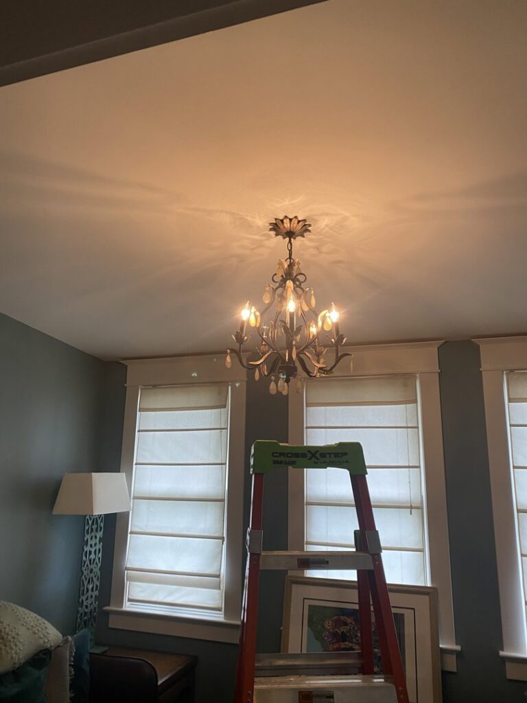 A decorative chandelier being installed with a ladder, showcasing lighting services by Peak Electric in Mount Washington, KY.