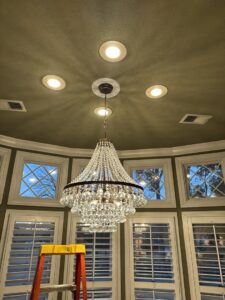 A large chandelier and recessed lighting installation with a ladder, by Delta Current Electric in Jonesboro, AR.