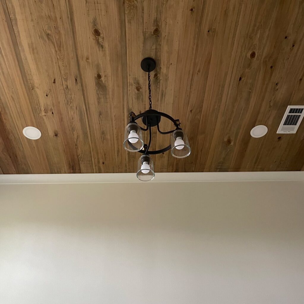A newly installed chandelier and recessed lighting fixtures on a wooden ceiling by Greater Baton Rouge Electric in Baton Rouge, LA.