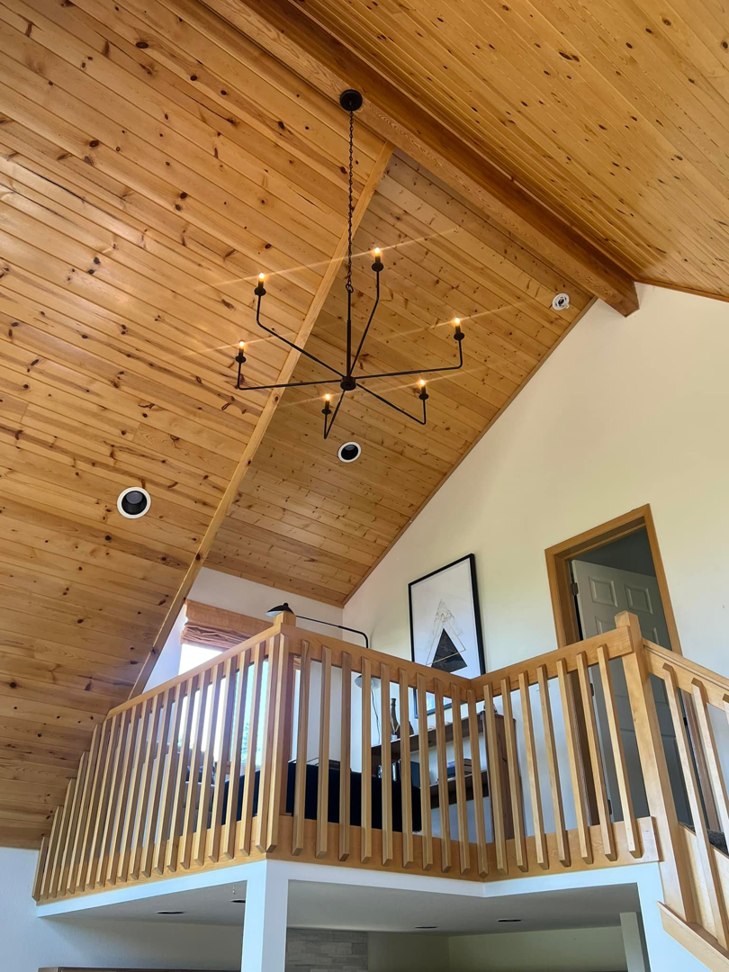 A modern chandelier and recessed lighting installed in a high-ceiling room by P&E Electric in Denver, CO.