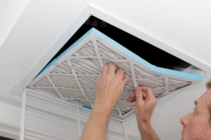 Hands changing an air filter in a ceiling HVAC vent, a service provided by Cool Concepts A/C & Heating in San Antonio, TX.