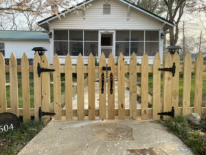 A charming wood picket fence with a functional gate installed in front of a residential home by Holmes Fence Company in Chattanooga, TN.