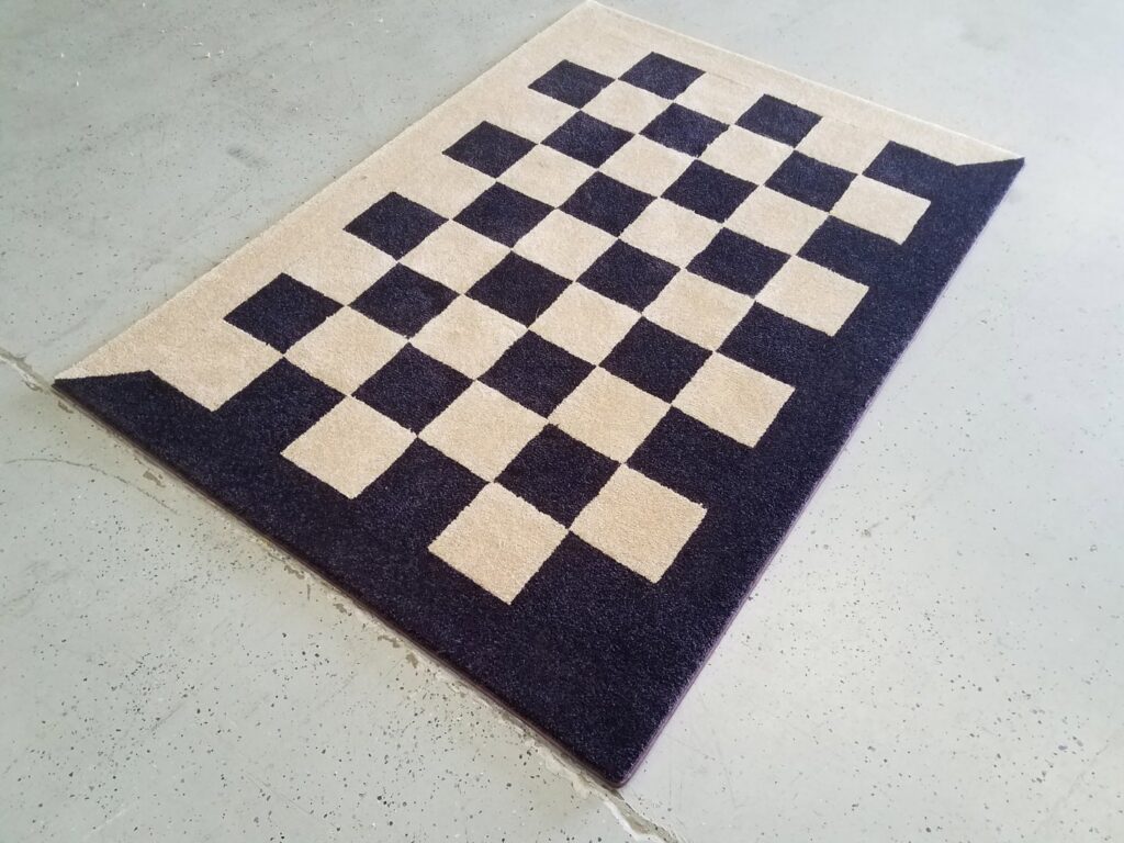 A custom checkerboard pattern area rug with bound edges, crafted by Carpet Binding By Scott in Oklahoma City, OK