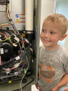 A child looking at the internal components of a furnace serviced by Summit Heating & Air Conditioning in White Bear Lake, MN.