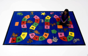 A child playing on a large, blue alphabet game carpet from Conexxo Kids Carpets in Miami, FL.