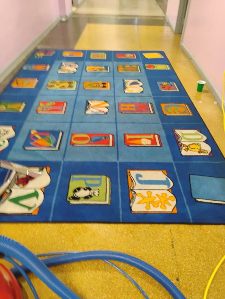 A children's alphabet rug after professional cleaning with equipment visible by Ready2go Professional Carpet & Upholstery Cleaning in Boston, MA