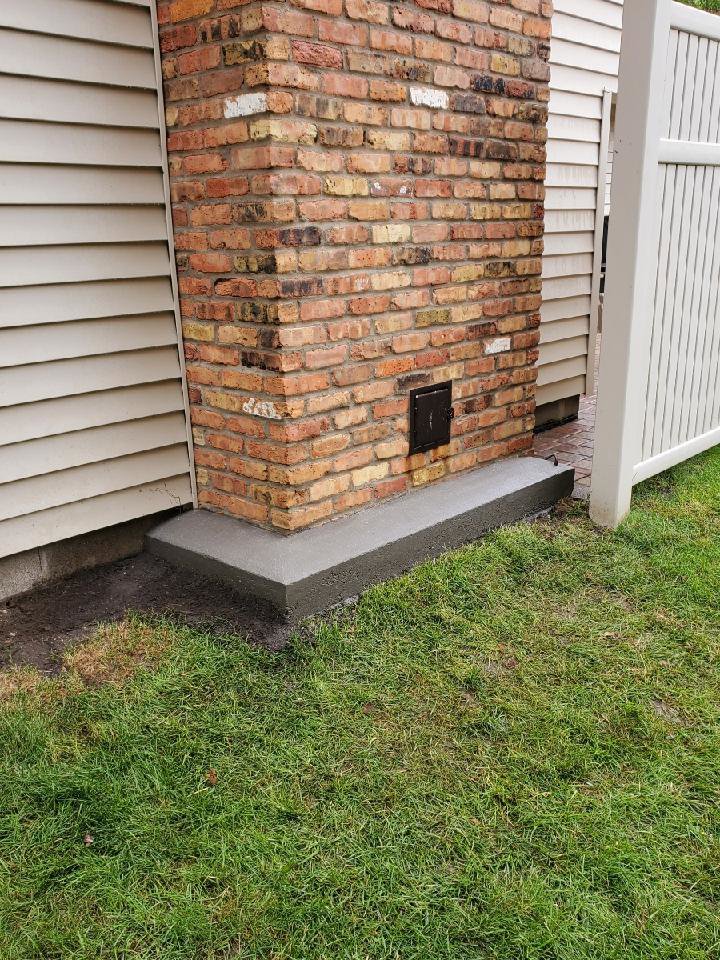 New concrete work completed at the base of a brick chimney by JJ Chimney Services in Minneapolis, MN.