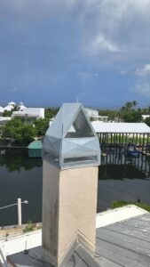 A metal chimney cap installed for wildlife exclusion on a house overlooking a waterway by The Wildlife Whisperer Inc in Cape Coral, FL