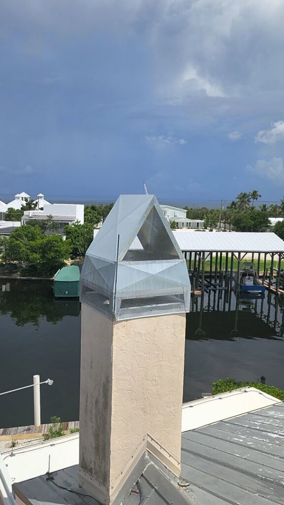 A metal chimney cap installed for wildlife exclusion on a house overlooking a waterway by The Wildlife Whisperer Inc in Cape Coral, FL