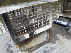 A new chimney cap being installed or sealed on a roof by Certified Masons in Warwick, RI