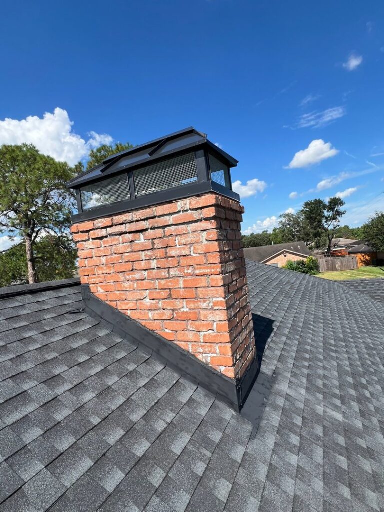 A newly installed chimney cap on a chimney with white siding by Brushers Chimneys in Houston, TX.