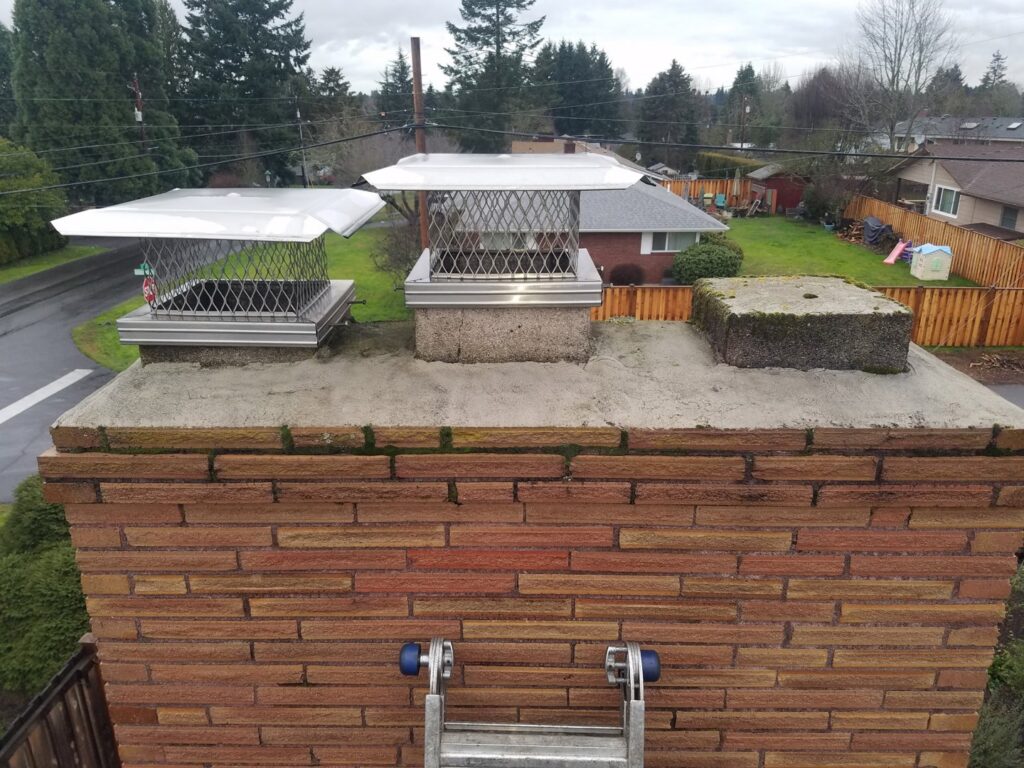 Two new metal chimney caps installed on a brick chimney with a ladder, by Matchbox Chimney Sweeps in Vancouver, WA.