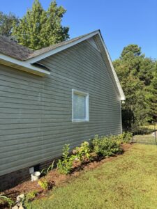 A chimney cleaning brush extending from the top of a residential chimney on a roof by A-1 Carolina Chimney Masters in Fayetteville, NC