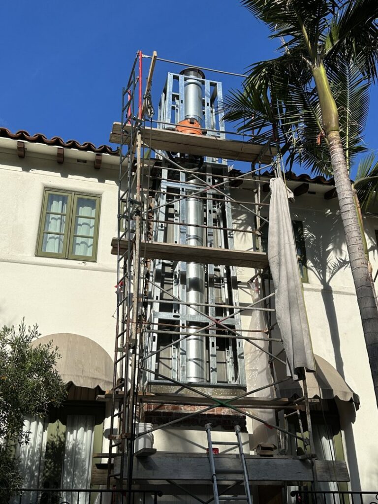 A tall chimney under construction with scaffolding, showcasing work by The Chimney Guy in Los Angeles, CA.