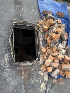 Chimney demolition or rebuild in progress on a roof with bricks and tarp by Royal Chimney's in Blue Ash, OH.