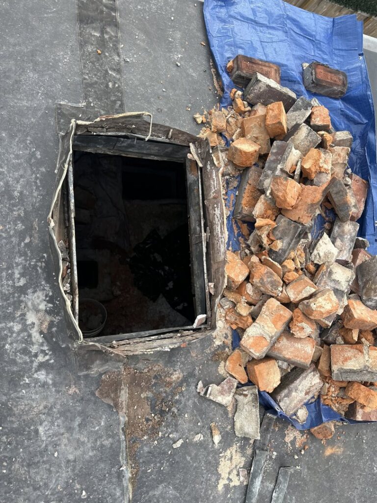 Chimney demolition or rebuild in progress on a roof with bricks and tarp by Royal Chimney's in Blue Ash, OH.