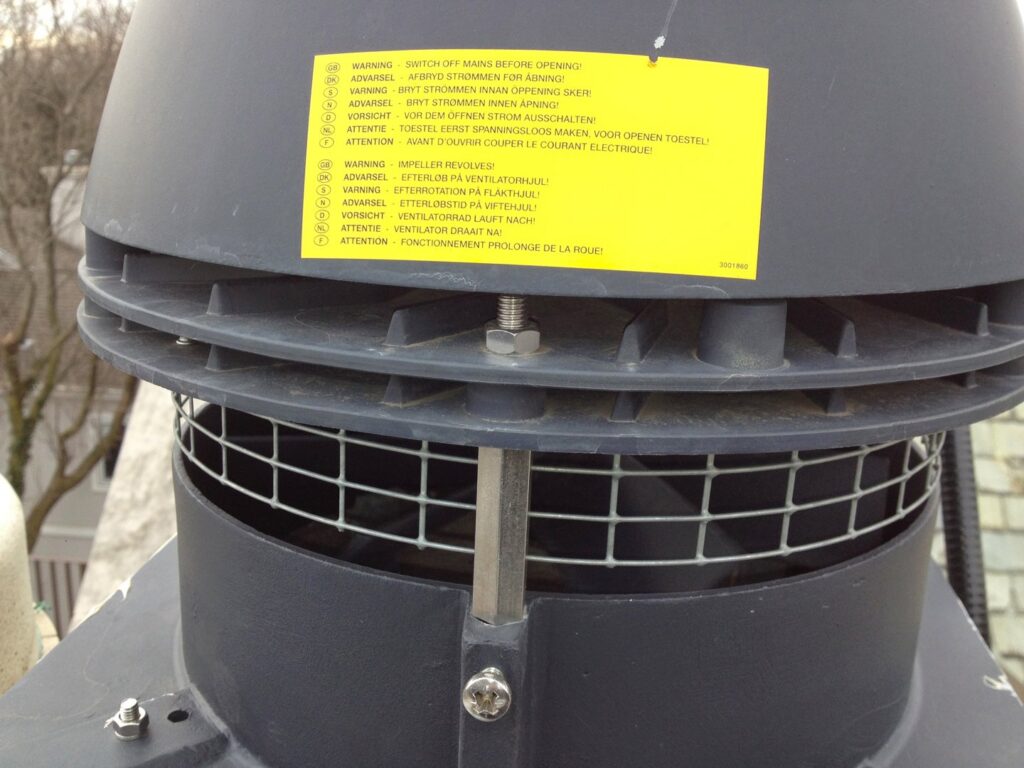 A close-up of a chimney fan or vent with a warning label, installed or serviced by Chimney Usa Inc in Chicago, IL.