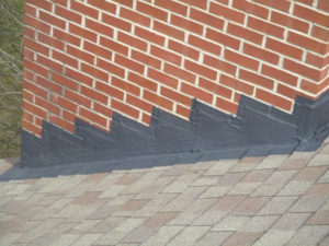 Close-up of repaired chimney flashing where a brick chimney meets the roof by The Mad Hatter in Raleigh, NC