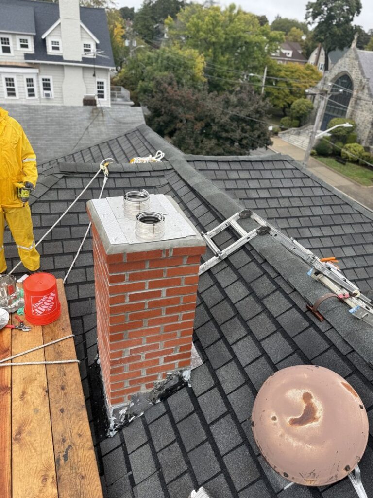 A Certified Masons worker on a roof installing chimney flues on a brick chimney in Warwick, RI
