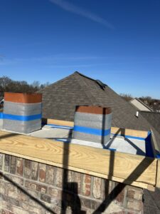 Two chimney flues wrapped in insulation and blue tape with new wooden framing, showing chimney repair or construction by Indy Ignited in Indianapolis, IN.